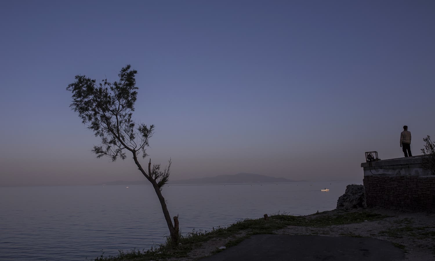 An economic migrant stands near the port of Mytilene on the Greek island of Lesbos close to an informal squat camp which is run by No Borders Kitchen, a European anarchist group.