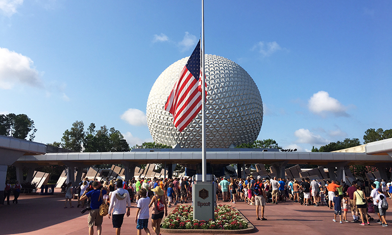 Tourists walk past a flag flown at half-mast in Epcot in Orlando. -AP