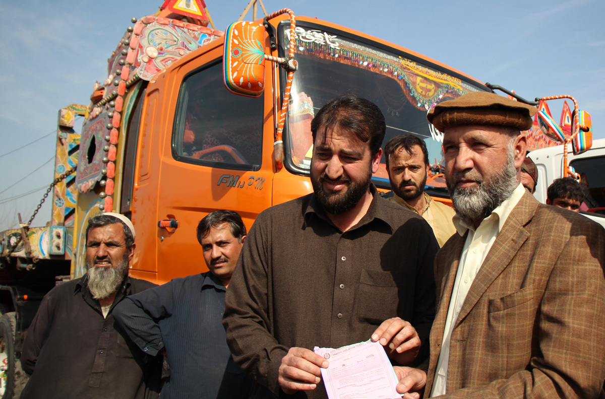 Ahmed Shinwari and his son hold a challan (ticket) that one of the drivers has received, Lahore