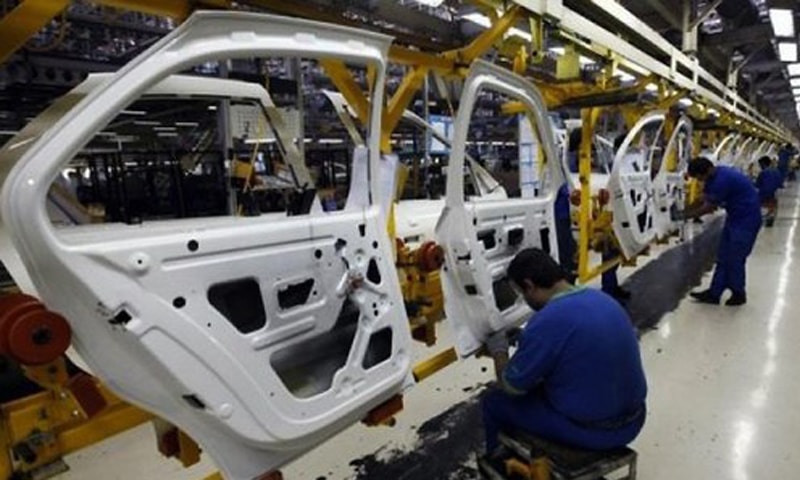 TECHNICIANS working on vehicles doors at a plant in this file photo.