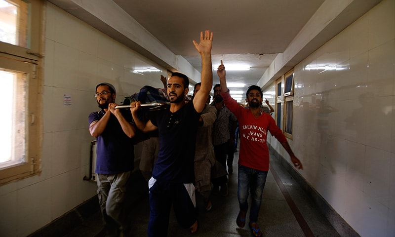 Kashmiris shout freedom slogans as they carry the body of a local. — AP