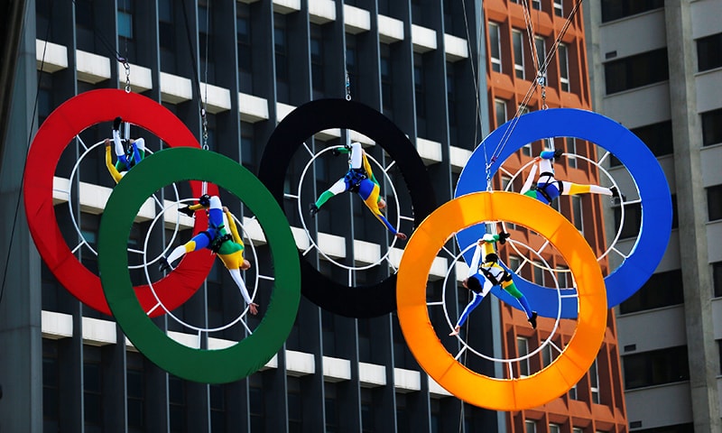 Acrobats perform on the Olympics rings at Paulista Avenue in Sao Paulo's financial center, Brazil. &mdash; Reuters