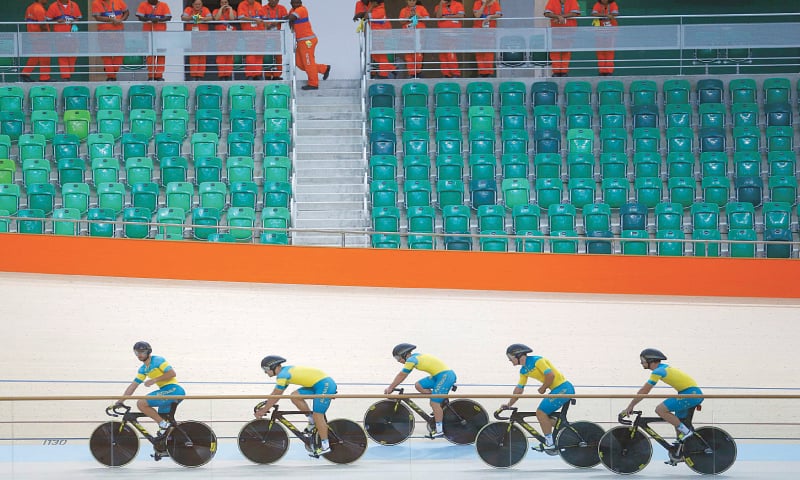 WORKERS watch as Australian cyclists train at the Olympic Park.&mdash;Reuters