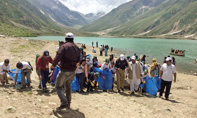 Participants of a walk collect garbage at Saiful Muluk Lake on Wednesday. &mdash; Dawn