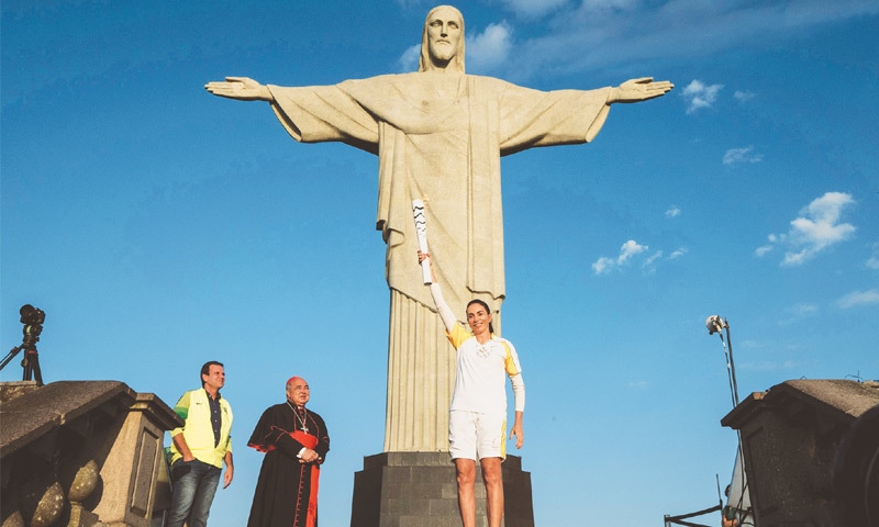 RIO DE JANEIRO: Olympic torch-bearer Brazilian former volleyball player Maria Isabel Barroso Salgado (R) holds up the torch of Rio Olympics with City Mayor Eduardo Paes (L) and Archbishop of Rio de Janeiro Orani Tempesta in front of the statue of Christo the Redeemer atop Corcovado Hill on Friday.—AFP RIO DE JANEIRO: Olympic torch-bearer Brazilian former volleyball player Maria Isabel Barroso Salgado (R) holds up the torch of Rio Olympics with City Mayor Eduardo Paes (L) and Archbishop of Rio de Janeiro Orani Tempesta in front of the statue of Christo the Redeemer atop Corcovado Hill on Friday.—AFP