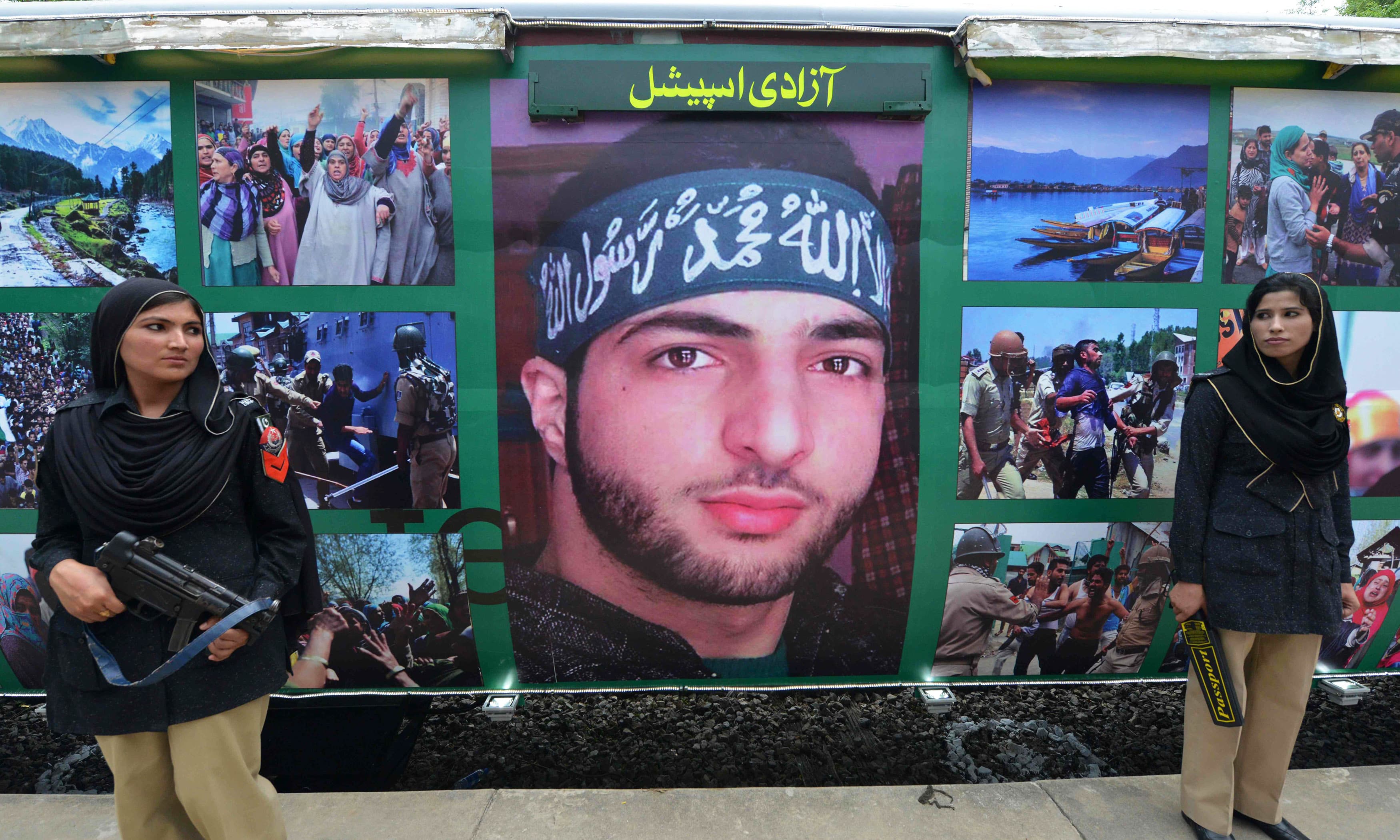 Policewomen stand guard beside a poster bearing the image of slain Hizbul Mujahideen commander Burhan Wani which adorns carriages of the Azadi Train. —AFP