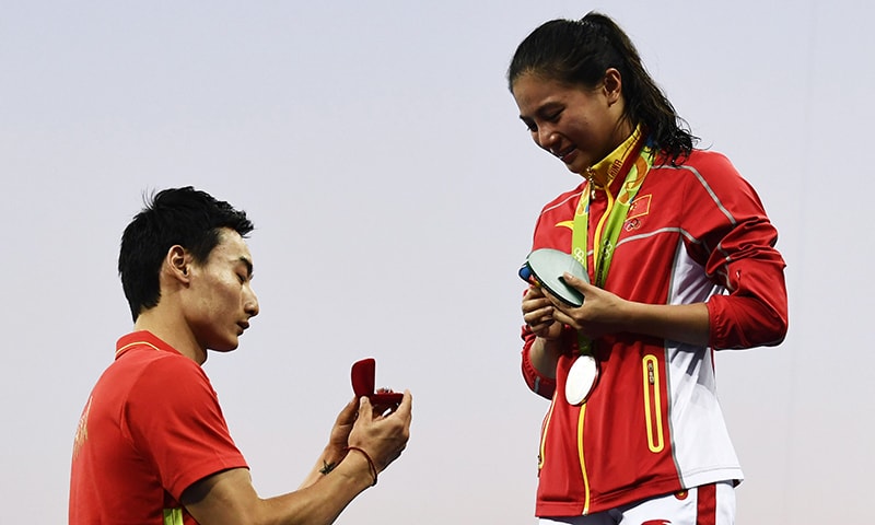 Silver medallist China's He Zi (R), reacts she receives a marriage proposal from Chinese diver Qin Kai during the podium ceremony. -AFP
