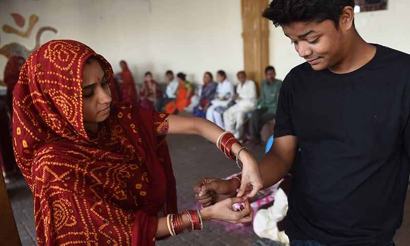 ایک ہندو لڑکی مذہبی تہوار مناتے ہوئے اپنے بھائی کے ہاتھ پر راکھی باندھ رہی ہے&mdash; فوٹو/ اے ایف پی