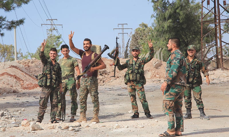 Aleppo: Syrian soldiers gesture on Sunday at a location on the southern outskirts of this city after regime forces retook control of three military academies from rebel fighters.—AFP