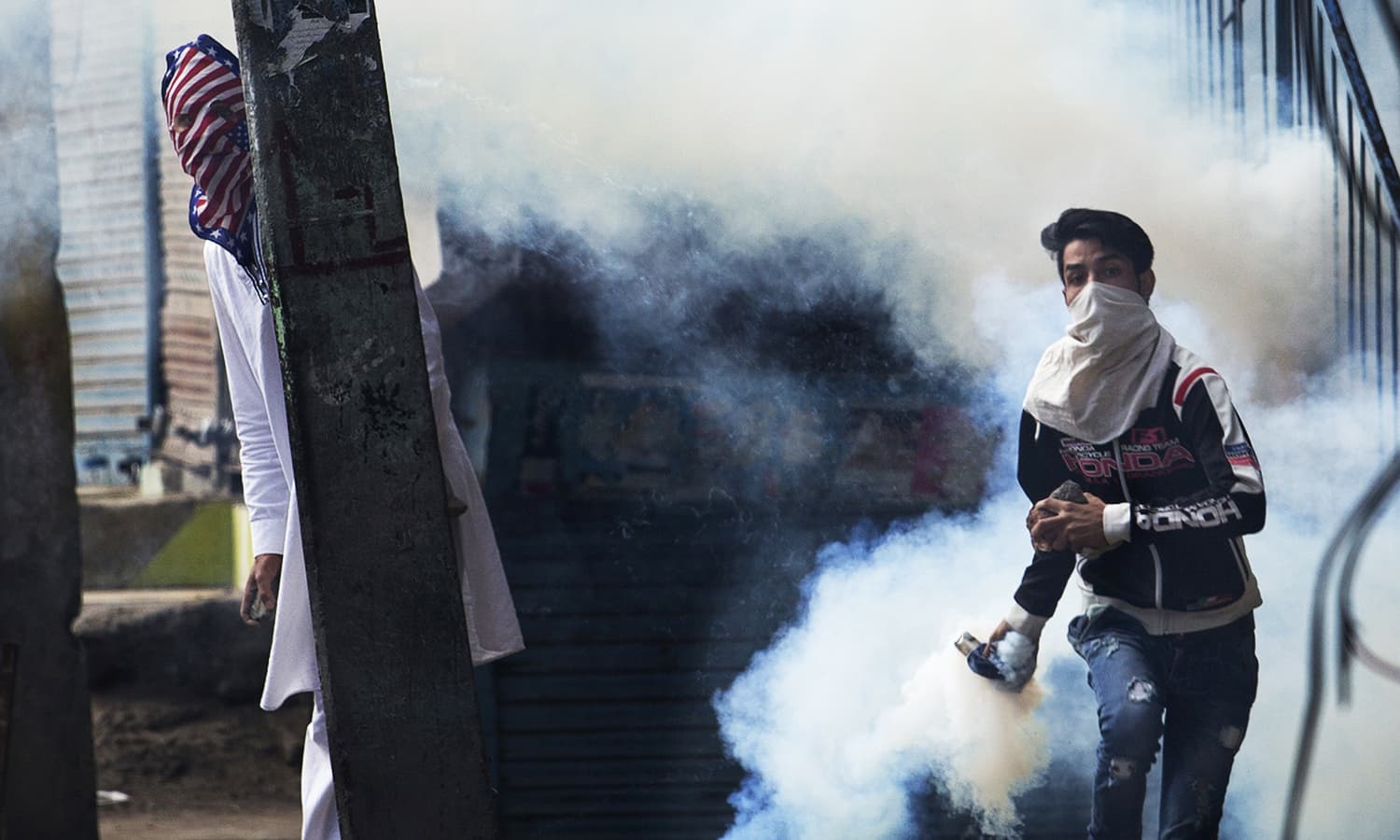 A Kashmiri protester prepares to throw back a tear gas canister at Indian security personnel as another takes cover behind an electric pole during a protest after Eid prayers in Srinagar, India-held Kashmir, Tuesday, Sept. 13, 2016. ─ AP