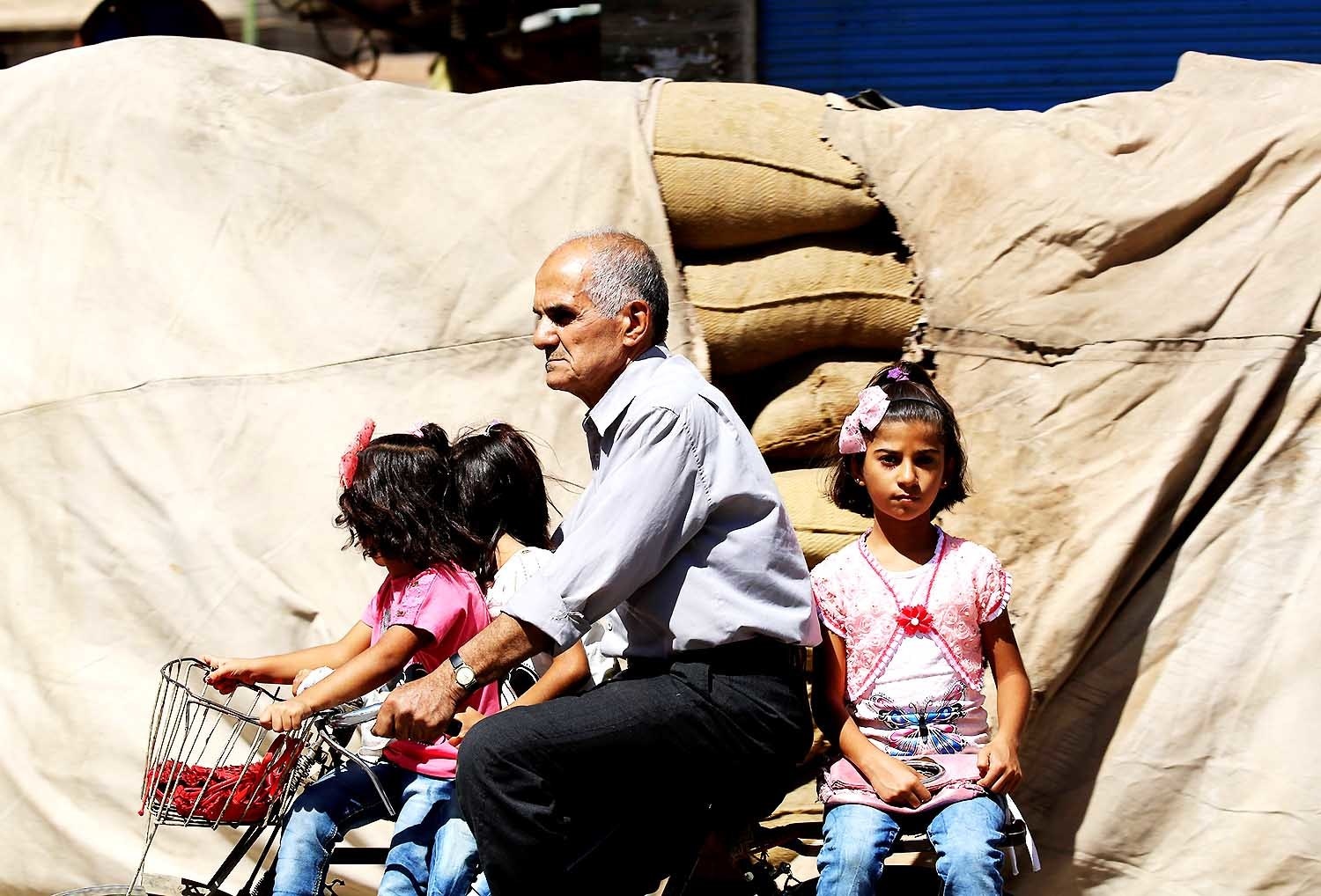 A man carries three girls on a bicycle in Qamishli. — AFP