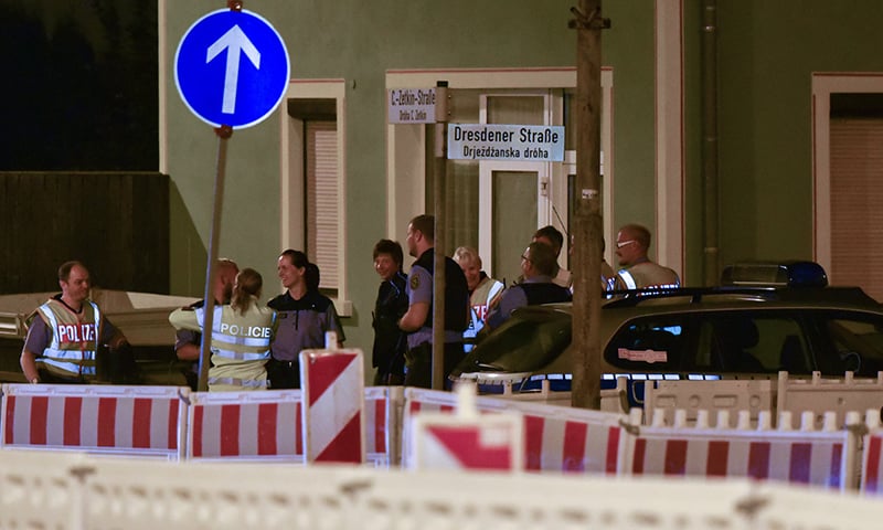 Police officers stand near a refugee shelter in Bautzen, after the clash between migrants and right-wing extremists ─  AFP