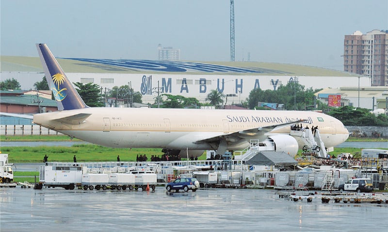 Manila: Security personnel stand under the Saudi Airline plane after one of its pilots released a distress signal before landing at Manila airport on Tuesday.—AFP Manila: Security personnel stand under the Saudi Airline plane after one of its pilots released a distress signal before landing at Manila airport on Tuesday.—AFP