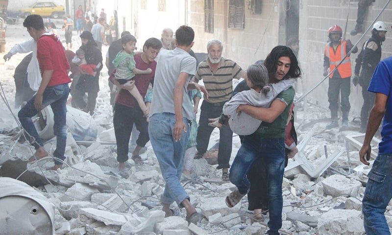 IDLIB: Syrian men carry injured people including children amid the rubble of destroyed buildings following a reported air strike on Thursday.&mdash;AFP