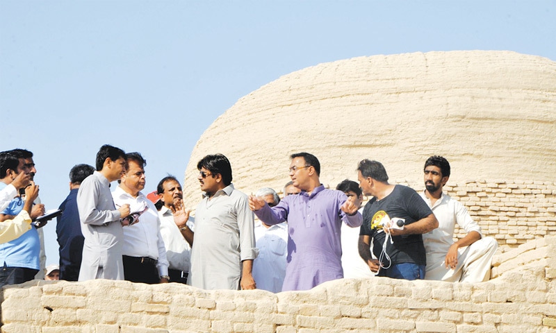 Minister for Culture Syed Sardar Shah (wearing sunglasses) gestures as he speaks to members of TCC in front of the stupa during a visit of the Moenjodaro city on Friday.&mdash;Dawn