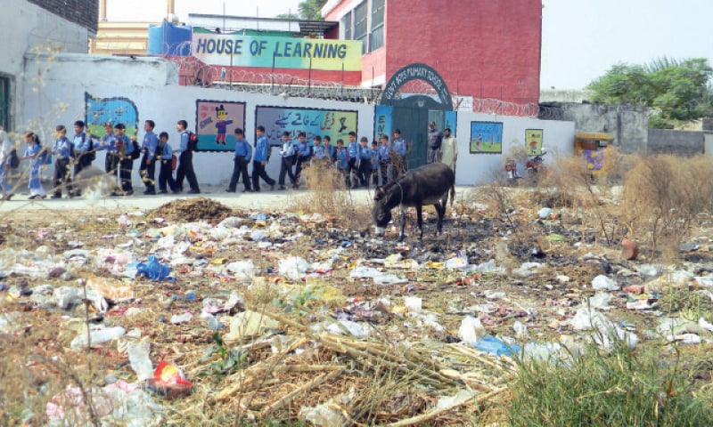 The primary school does not even have rugs for the students to sit on. The other picture shows heaps of garbage near the institution. &mdash; Dawn