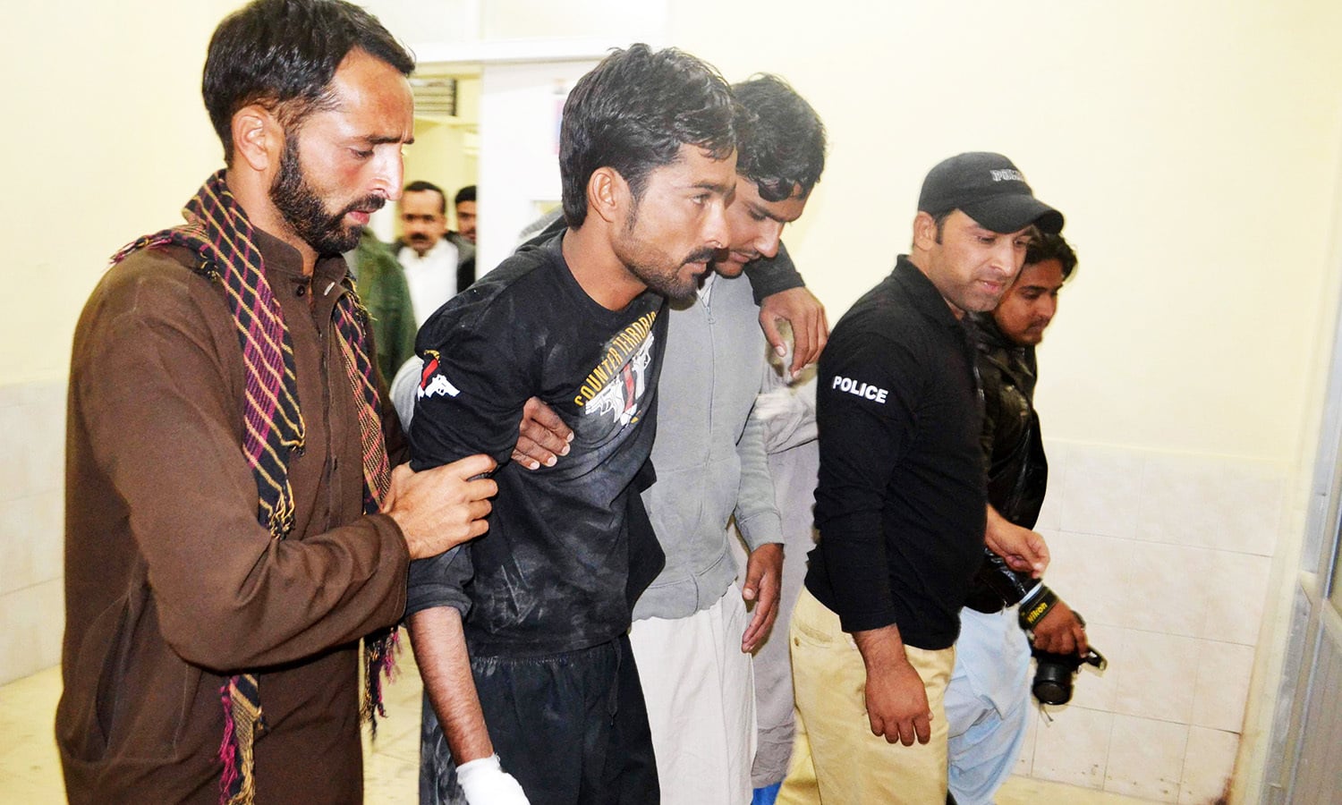 Police help an injured colleague into the hospital after militants attacked the Balochistan Police College in Quetta on October 25. — AFP