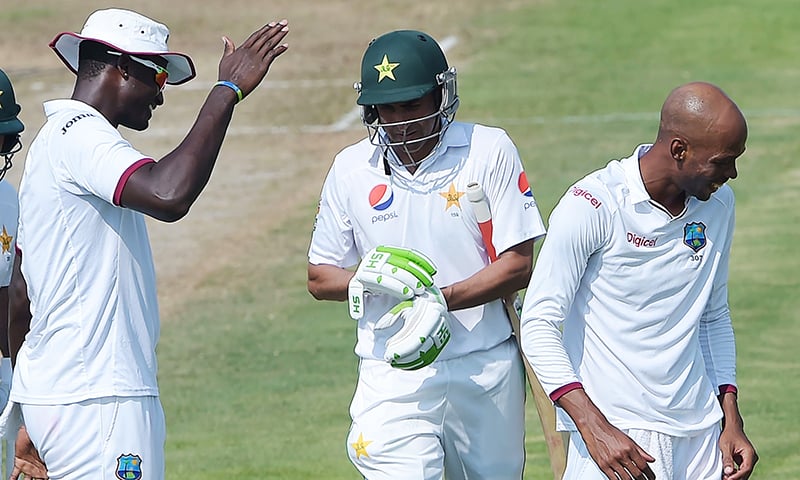 West Indies' cricket captain Jason Holder and teammate Roston Chase celebrate after the dismissal of Younis Khan on the first day of the third and final Test between Pakistan and West Indies. -AFP