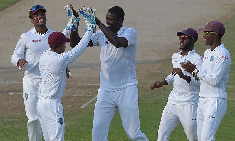 Jason Holder celebrates with teammates after taking the wicket of Younis Khan. ─AFP