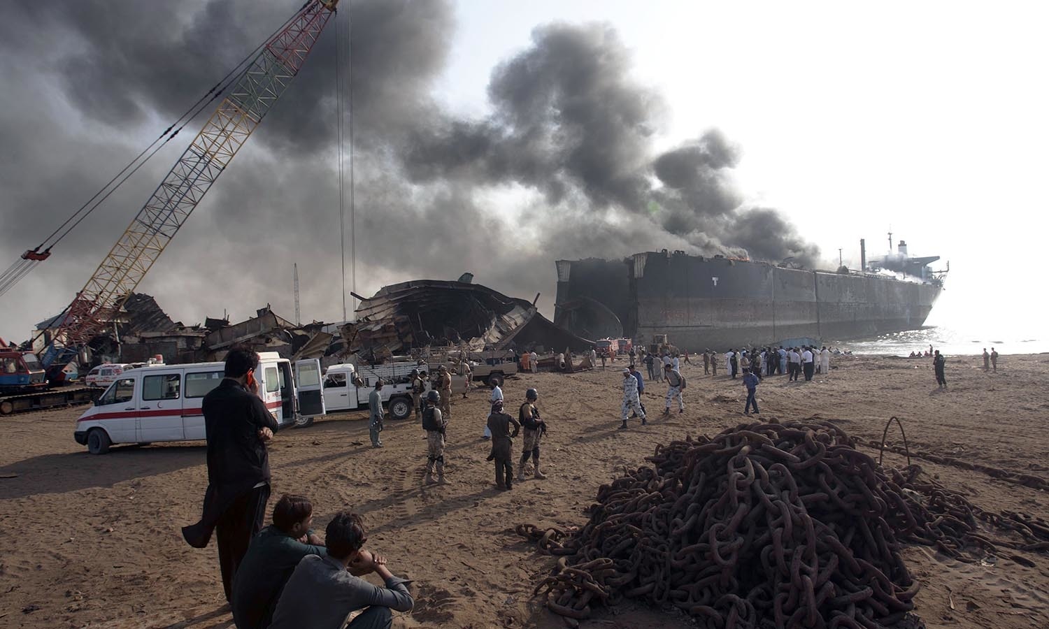 People look at the ship on fire following an explosion in the coastal town of Gadani. ─AP