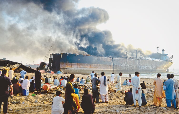 SHIP-BREAKING workers at Gadani helplessly watch the fire from afar as first responders and rescue teams remain unable to do anything until the oil inside the tanker burns up or evaporates.—Fahim Siddiqi/White Star