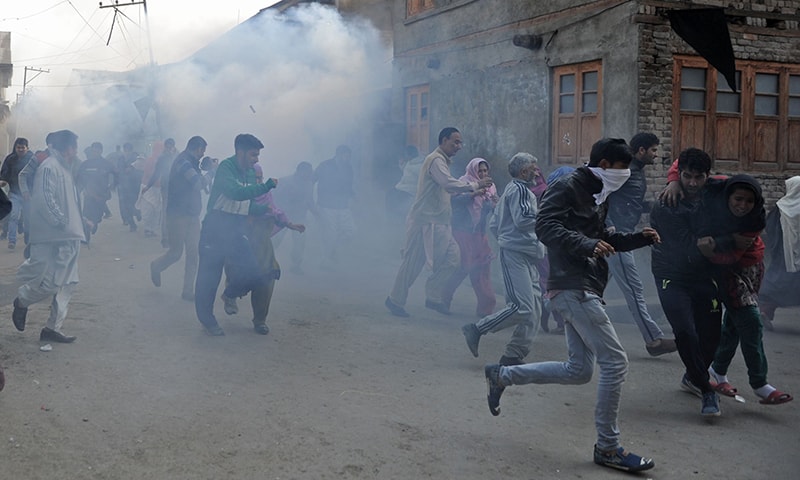 Kashmiri protesters run after Indian police fired teargas shells and pellets during the funeral procession for Qaiser. ─ AFP