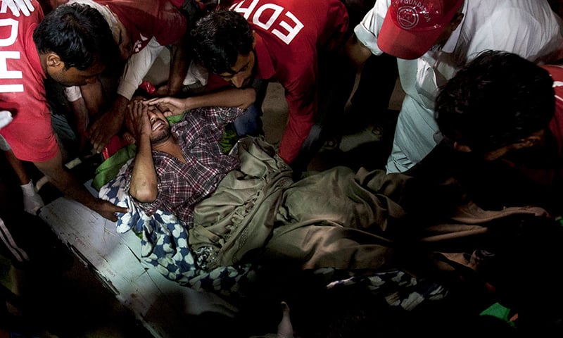 Rescue workers and volunteers unload an injured victim of bomb blast. -AP