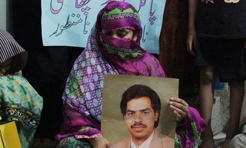 بورے والا میں احتجاج کے دوران امداد علی کی اہلیہ صفیہ بانو اپنے شوہر کی تصویر لیے بیٹھی ہے&mdash;فائل فوٹو / اے پی