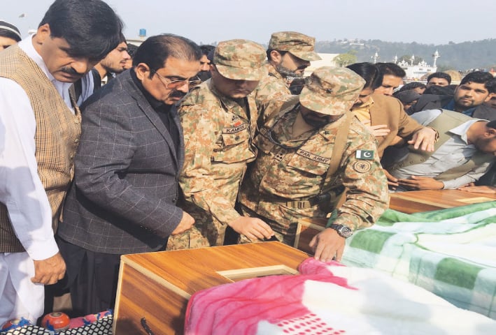 LEADER of Opposition in AJK Legislative Assembly Chaudhry Mohammad Yasin (second left), army officials and local people have a last glimpse of the children killed in Indian shelling before their burial in Singhaal village on Sunday.—Dawn