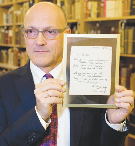 HAARLEM: Thijs Blankevoort, director of Bubb Kuyper auction house, holds a short poem by Anne Frank, handwritten and dated in Amsterdam on March 28, 1942, prior to the auction in the Netherlands on Wednesday.—AP