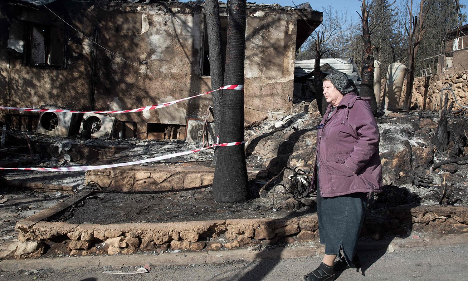 ایک خاتون اسرائیلی بستی سے گزر رہی ہے جس میں لگنے والی آگ نے مکانات کو مکمل طور پر تباہ کردیا &mdash; فوٹو: اے ایف پی