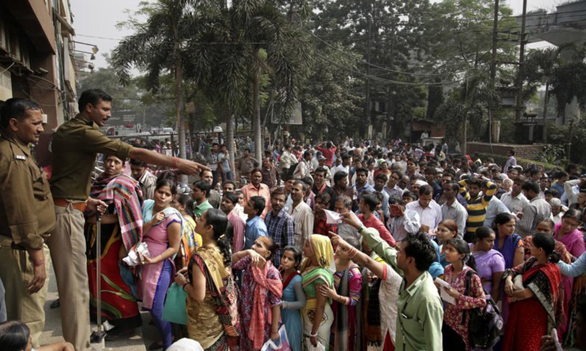 An Indian policeman asks people to wait patiently in queues to exchange or deposit discontinued currency notes, outside a bank in in New Delhi, India | AP