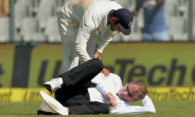 ہندوستانی فیلڈر چتیشور پجارا سر پر گیند لگنے کے سبب زخمی ہونے والے آسٹریلین امپائر کی خیریت دریافت کر رہے ہیں&mdash; فوٹو: اے ایف پی