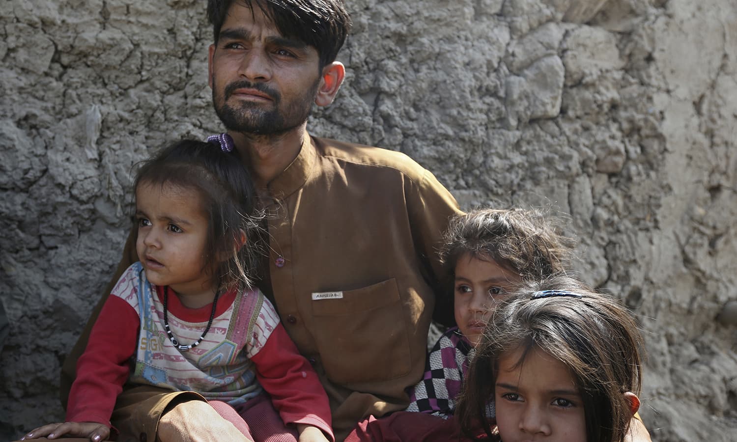 A displaced Afghan man with his children watches an acrobatic display during a juggling competition in Kabul. — AP