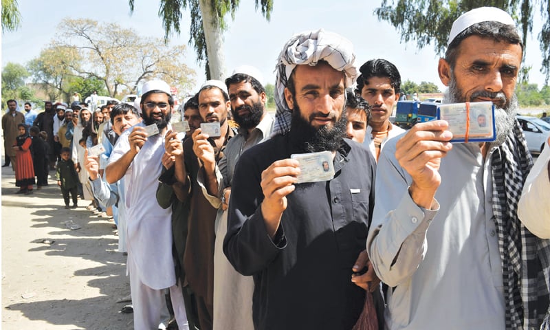 Many refugees still stick to the legal route: Afghan refugees show their Proof of Registation cards while waiting outside the Chamkani Registration Centre, Peshawar to register their newborn children