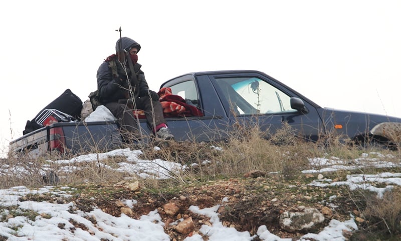 A militant sits in the back of a truck as he is evacuated from Aleppo. -AFP