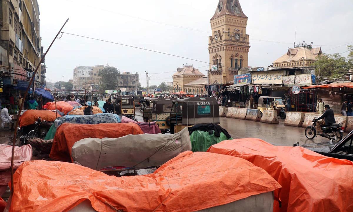 Vendors cover items on their handcart during rain in the port city. —Online