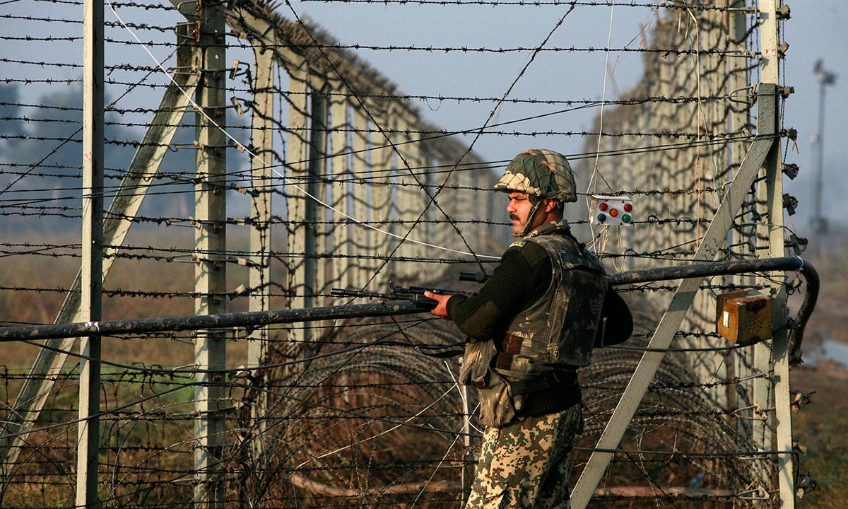 An Indian Border Security Force soldier patrols the fenced border with Pakistan in Suchetgarh, located southwest of Jammu and Kashmir | Reuters