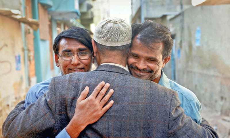 Bhatti (left) and Sulaiman finally have something to smile about as they embrace their cousin outside his home in Karachi.— Fahim Siddiqi/ White Star