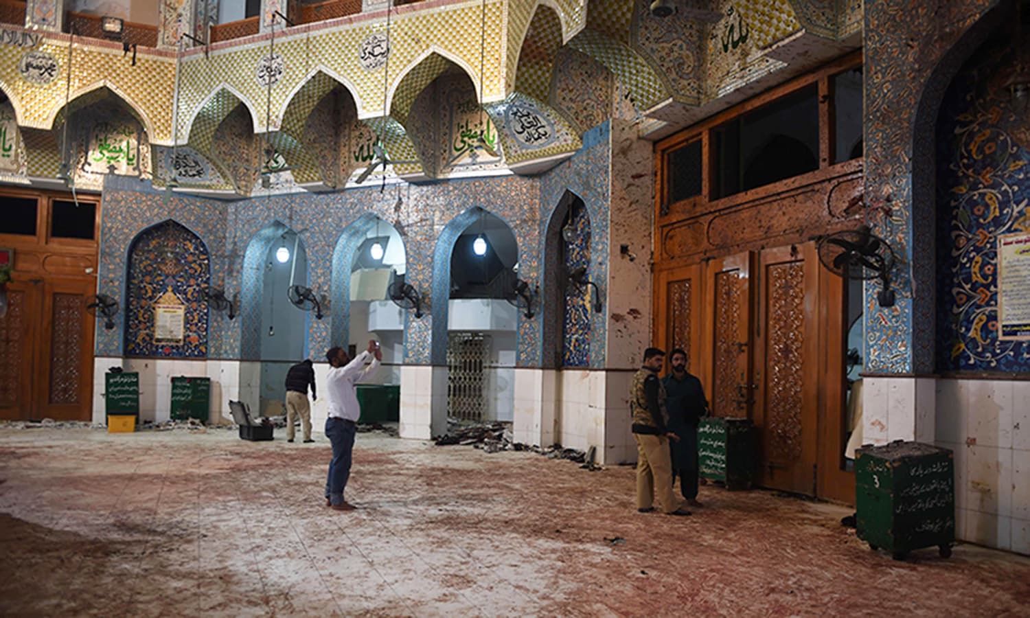 Pakistani security officials inspect the blood-stained floor a day after a bomb attack hit the Lal Shahbaz Qalandar shrine in Sehwan. ─AFP