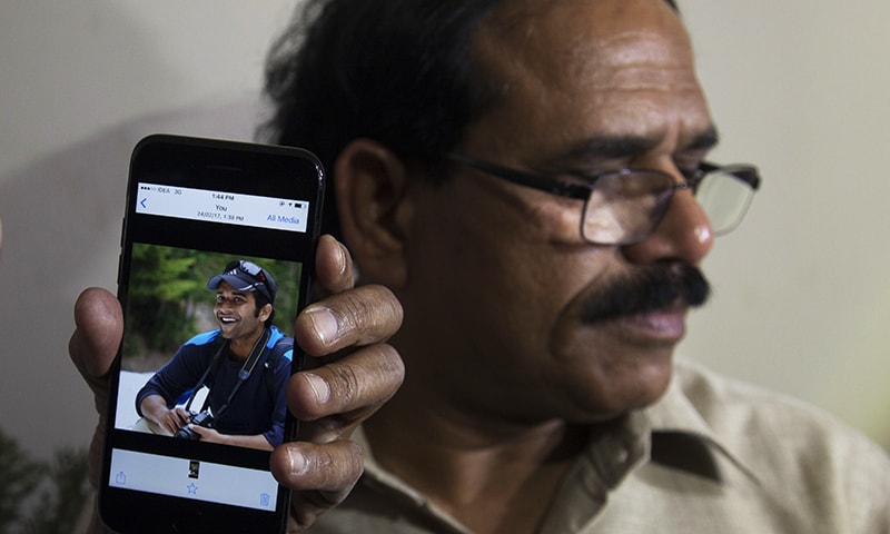 A man shows a picture of Alok Madasani, an engineer who was injured in the shooting. -AP