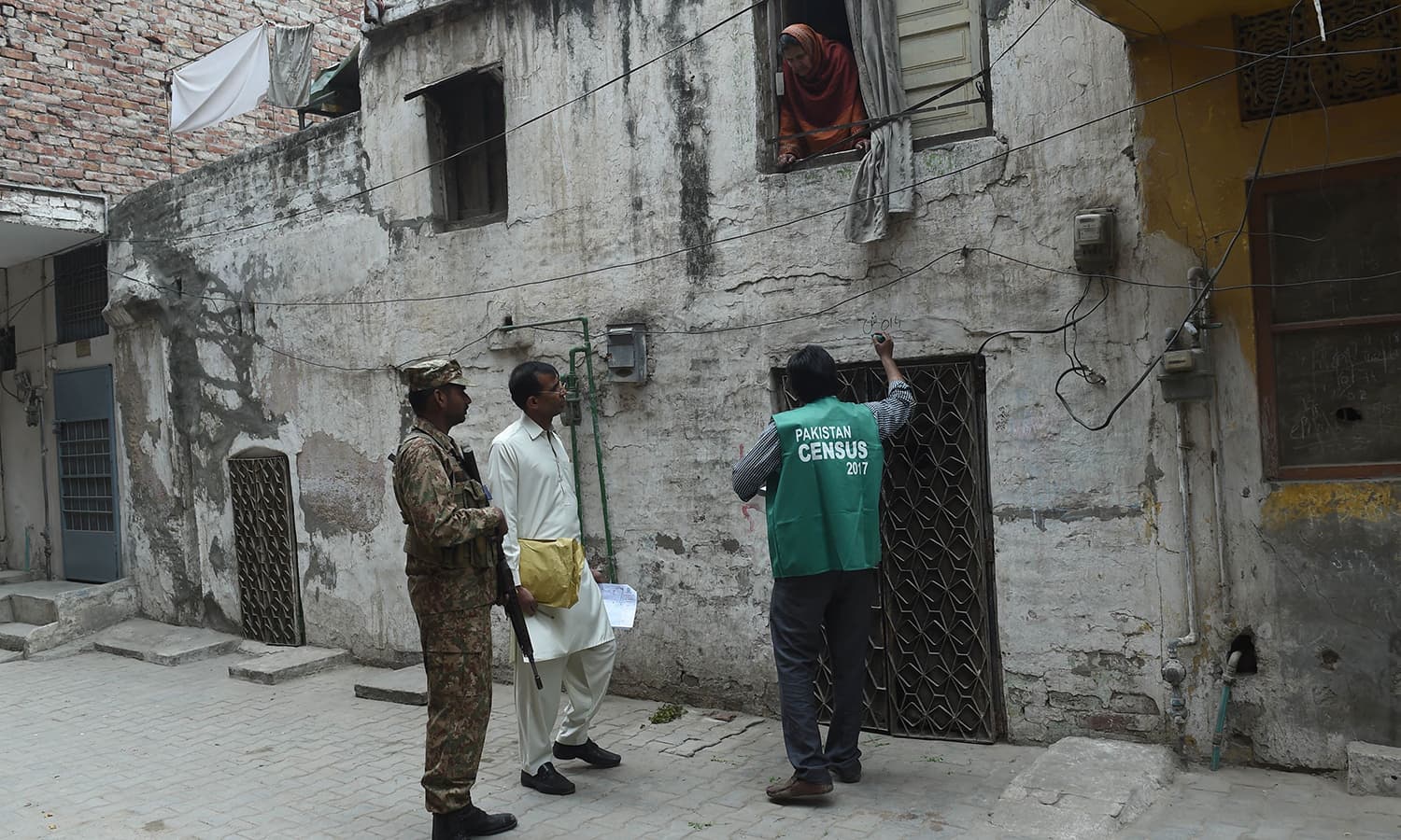 A woman interacts with an official from the Pakistan Bureau of Statistics as an army soldier stands guard in Lahore. — AFP