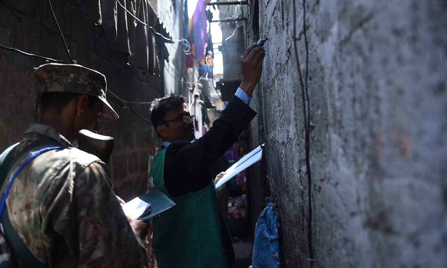 An enumerator marks a house after collecting information from a resident during a census in Karachi. — AFP