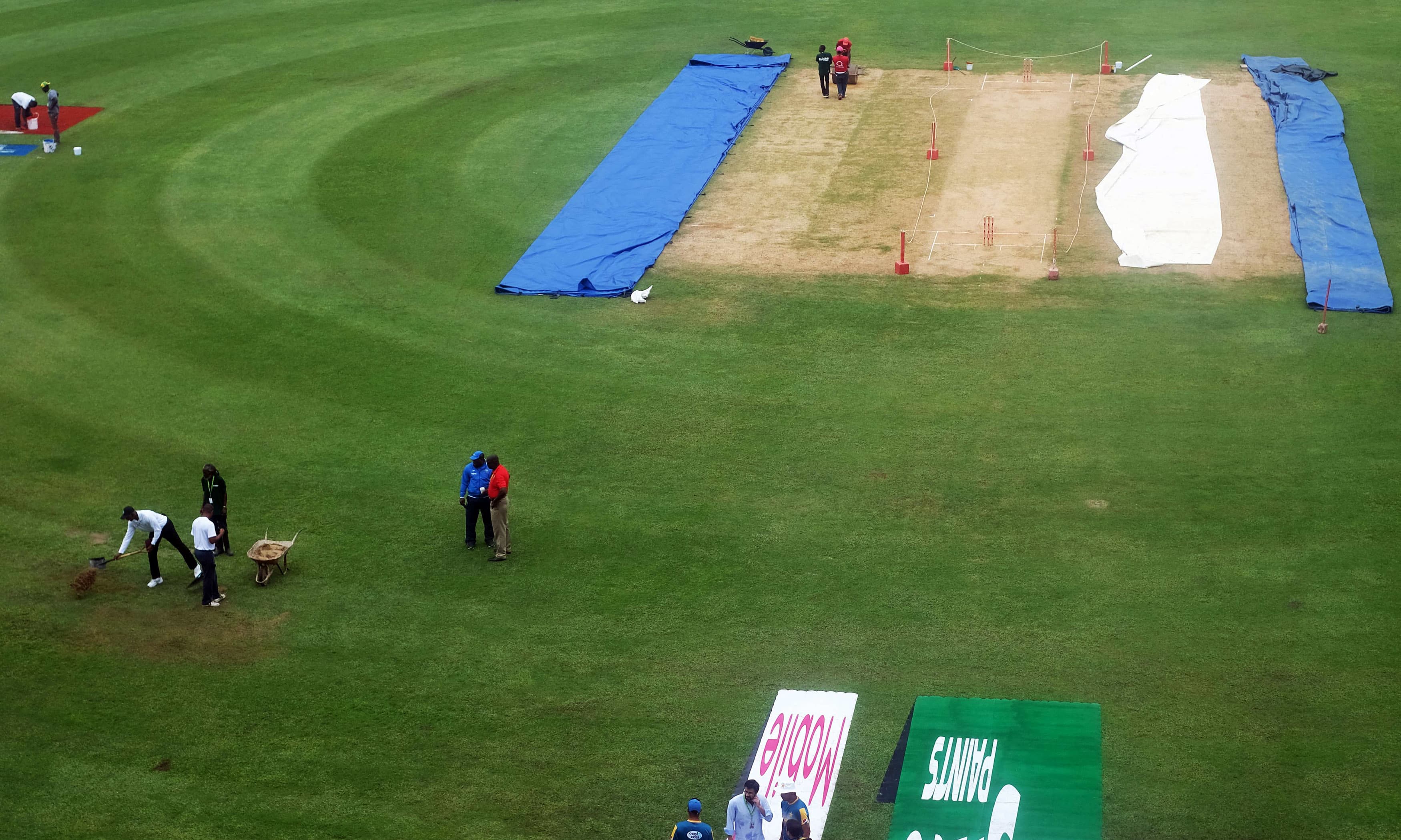 Groundsmen spread sand over part of the wet outfield before the start of day three. &mdash;AFP