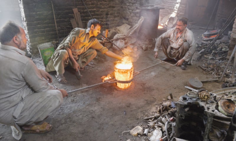 Workers bring out hot iron from the burner. Salt is later sprinkled on the metal and cleaned.