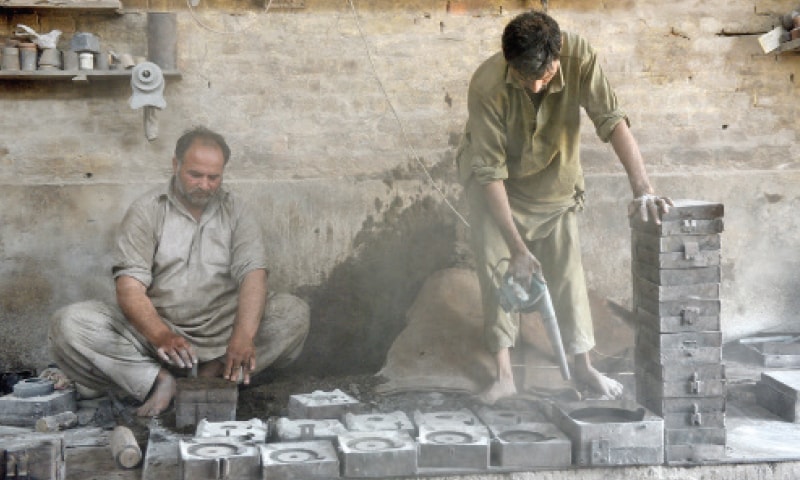 Workers adjust moulds before pouring the molten metal.