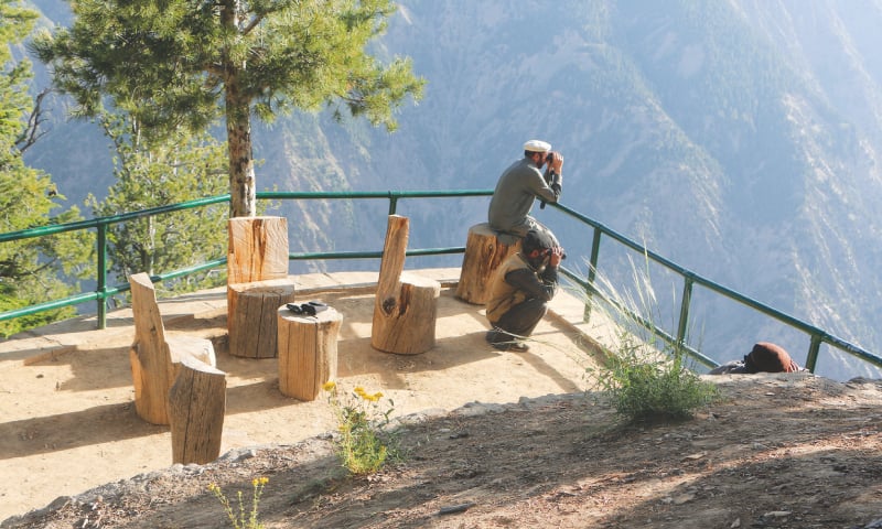 A man looking through binoculars at the lookout point at the Chitral Gol National Park.