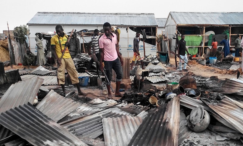 Armed members of a local defence group inspect the damages of a suicide blast in Maiduguri on June 8.— AFP Armed members of a local defence group inspect the damages of a suicide blast in Maiduguri on June 8.— AFP