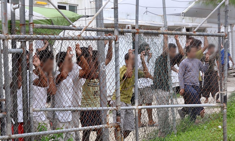 Asylum-seekers look through a fence at the Manus Island detention centre in Papua New Guinea.─AAP