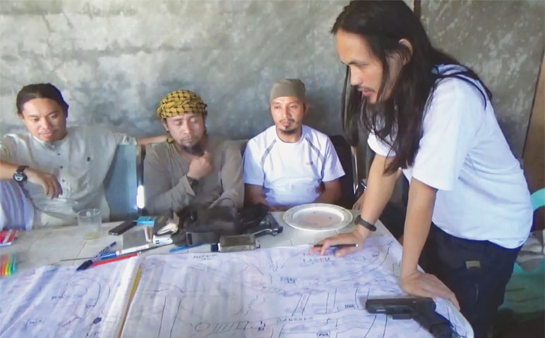 THIS screen grab taken from a handout video released by the Philippine Army on Sunday shows Abdullah Maute (right) looking at an improvised map of Marawi, while Isnilon Hapilon (second left), leader of hard-line group Abu Sayyaf, looks on, as they plan an attack on Marawi city at an undisclosed location on Mindanao island.—AFP